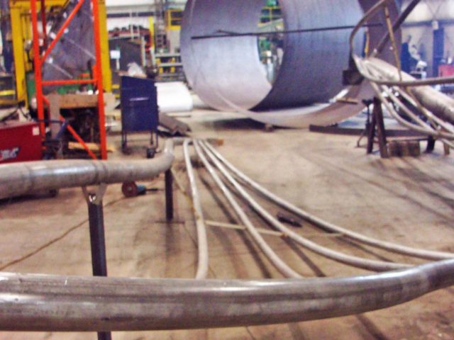 The Public Art Sculpture "Rafaga Unleashed" Installed At The Pier 8 Waterfront Park In Hamilton, Ontario, Canada Is Under Construction At Kubes Steel Featuring Custom Rolled And Fabricated Stainless Steel Sections For The "Sail" Portion