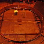 Overhead Aerial View Of A Circular Metal Fabrication Being Welded In A Workshop For A Penstock (Draft Tube Liner)