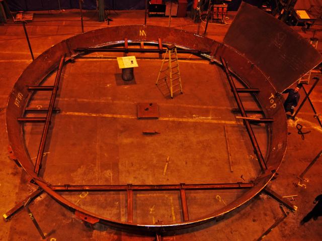 Overhead Aerial View Of A Circular Metal Fabrication Being Welded In A Workshop For A Penstock (Draft Tube Liner)