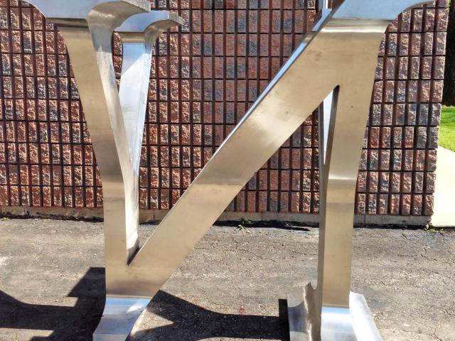A Shiny Stainless Steel Sculpture Of A Central Letter "N" Which Changes Into The Letter "Y" At Each Side