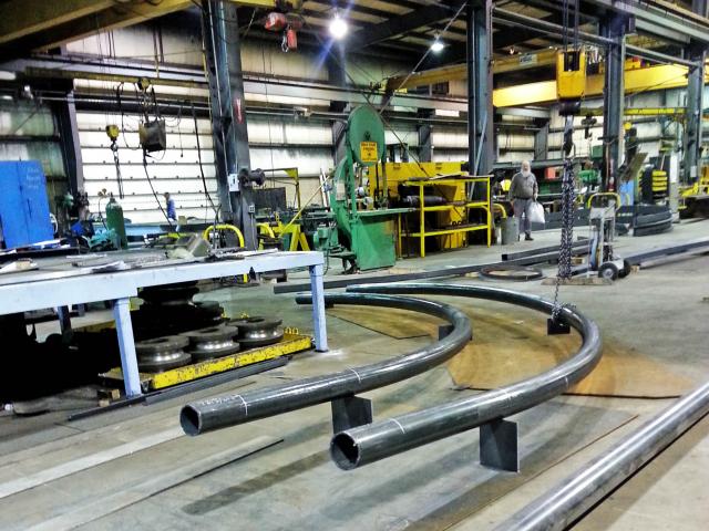 A Pair Of Custom Rolled Pipes Intended For Roller Coaster Rails. They Maintain Equal Distance From Each Other Through A 90 Degree Turn.
