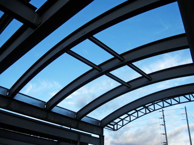 Looking Up At Rolled Steel Structural Roof Sections Against A Blue Cloudy Sky