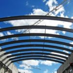 Looking Up At Rolled Steel Structural Roof Sections In Front Of A Cloudy Blue Sky