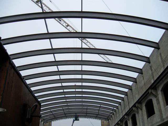 Looking Up At Rolled Steel Structural Roof Sections With A Construction Crane In The Background