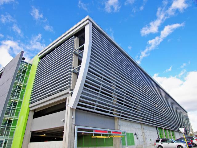 The Side Of A Building With Curved Beams Covered With Shades To Create An Accent Feature