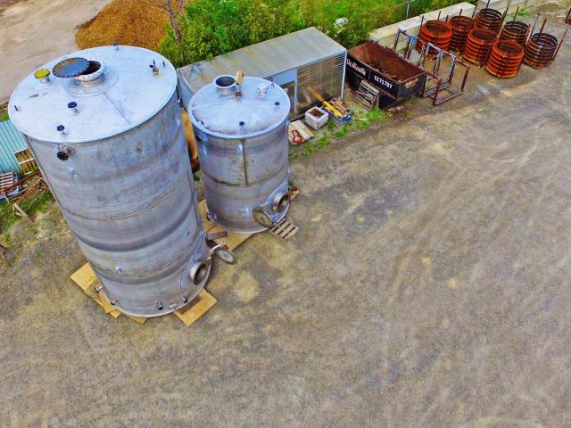 An Aerial View Of Two Vertical Cylindrical Vessels For Bisulfate Storage With Flange Attachments And Hatch Doors That Bolt Closed Sit Completed In A Yard