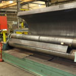 A Worker Rolls Sheet Steel For Oil Vat Troughs In The Shop At Kubes Steel