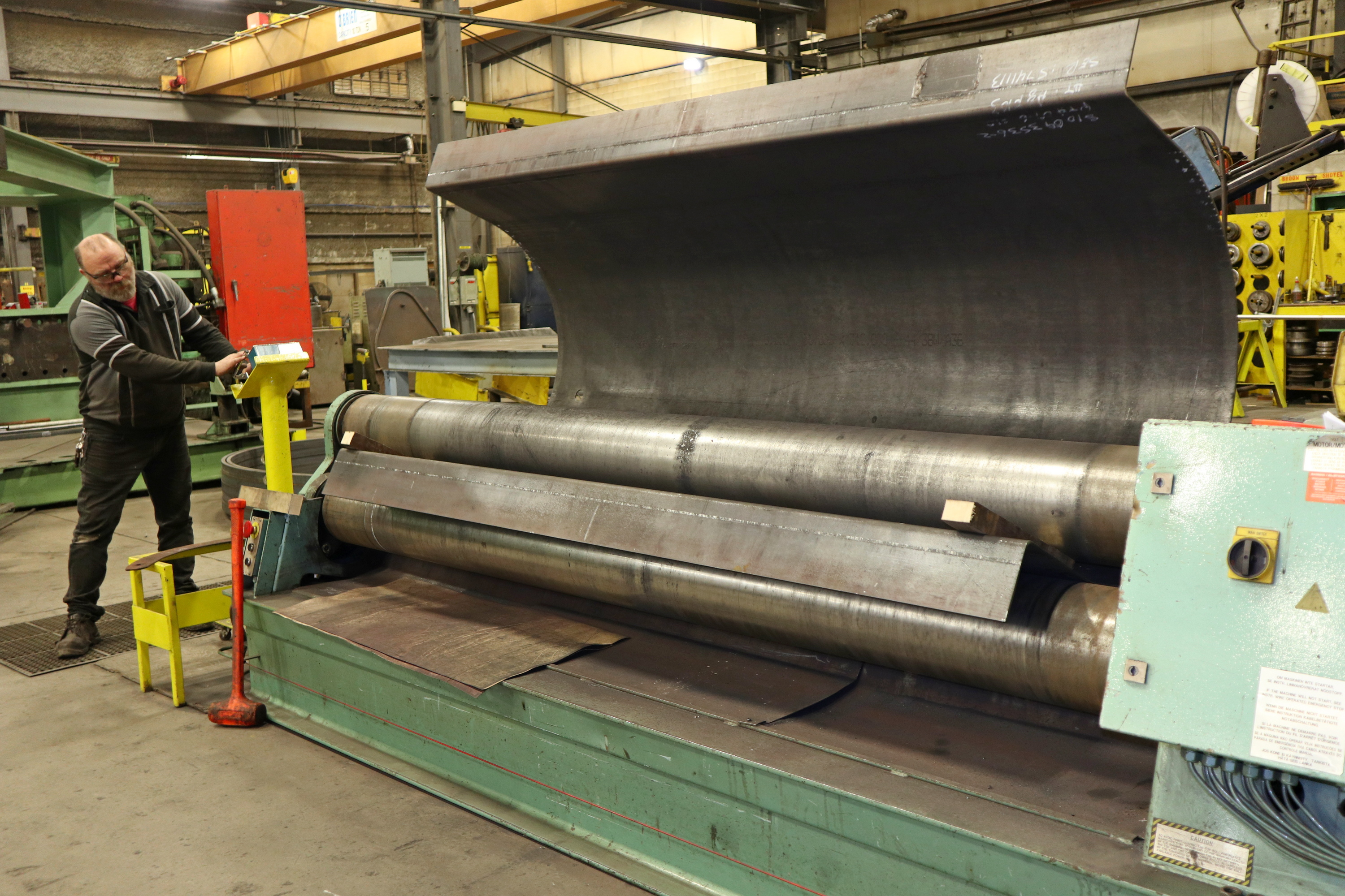 A Worker Rolls Sheet Steel For Oil Vat Troughs In The Shop At Kubes Steel
