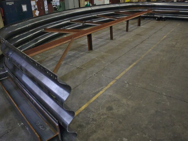 Custom Curved Sections Of Corrugated Steel Are Fabricated Into A Large Half Circle Assembly With Internal Bracing Beams