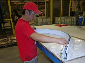 Un trabajador compara un canal de aluminio doblado personalizado con una plantilla en un taller de acero de Kubes