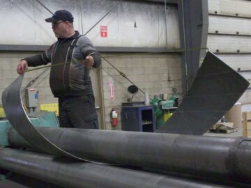 Un ouvrier vérifie un limon d'escalier fabriqué sur mesure pendant le laminage de plaques chez Kubes Steel